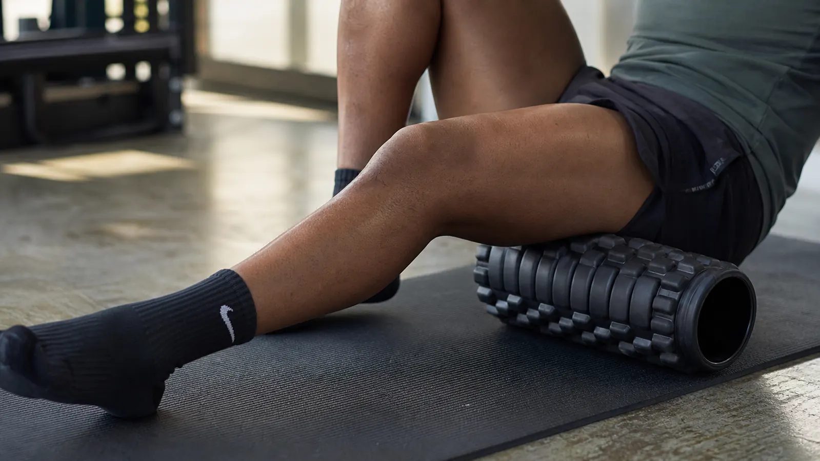 Runner using foam roller on IT band on a track infield after a run